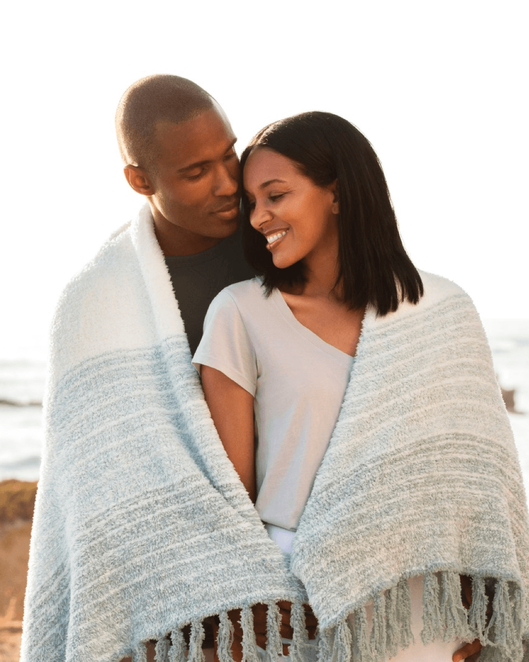 man and woman are hugging covered with one blanket